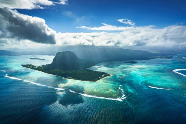 Aerial view of Mauritius Island with clear turquoise waters and lush green landscape under a partly cloudy sky