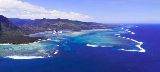 Aerial view of Mauritius Island with turquoise waters and mountains under clear sky