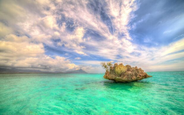 Small rocky islet with vegetation surrounded by turquoise water in Mauritius Island