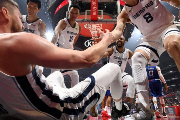 Memphis Grizzlies players helping a teammate to stand up during a basketball game