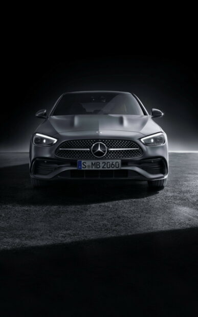 Front view of a luxury Mercedes Benz car with illuminated headlights on a dark background