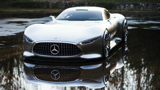 A sleek silver Mercedes Benz car is reflected in the water showcasing its modern design and grille