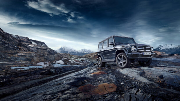 Black Mercedes Benz SUV parked on rocky terrain with mountains in the background