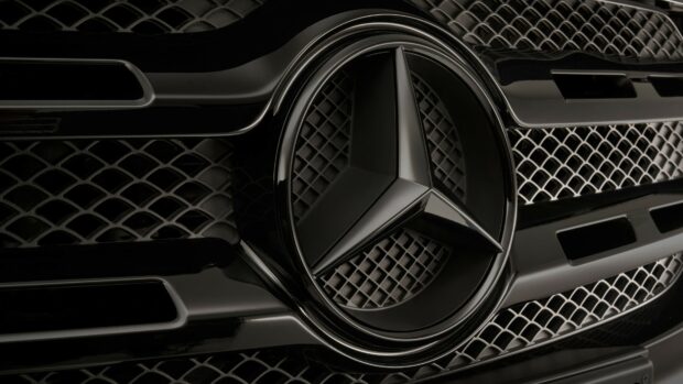 Close up of Mercedes Benz emblem on black car grille showing intricate details