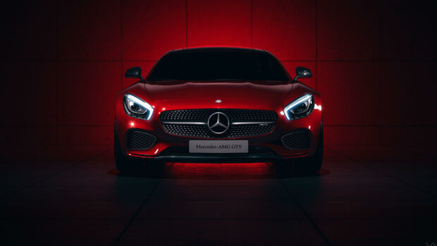 Front view of a red Mercedes Benz car with illuminated headlights and grille