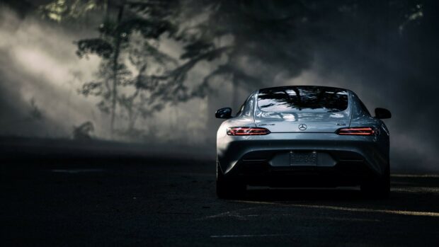 Mercedes Benz sports car driving on a dark road with mist and trees in the background