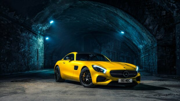 Yellow Mercedes Benz car parked inside an illuminated dark tunnel with brick walls