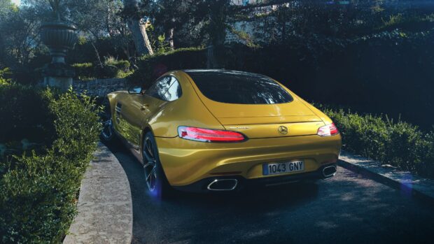 Yellow Mercedes Benz car parked on a winding road surrounded by greenery and trees