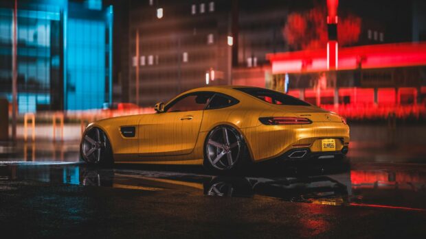 Yellow Mercedes Benz sports car parked on wet city street at night