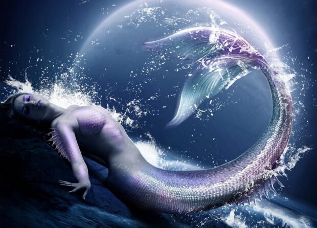 A beautiful mermaid resting on rocks with splashing water around her tail