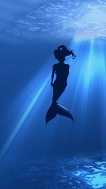 A mermaid silhouette swimming underwater with light rays shining through the water