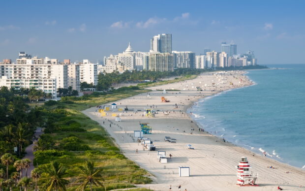 Miami Beach skyline with sandy beach and tall buildings under blue sky