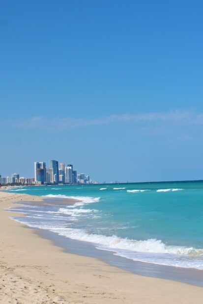 Clear view of Miami Beach skyline along the turquoise ocean shore at sunny day