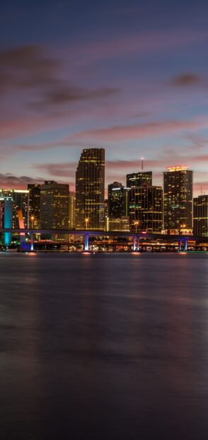 Miami Beach skyline viewed at dusk with illuminated buildings and calm water reflection