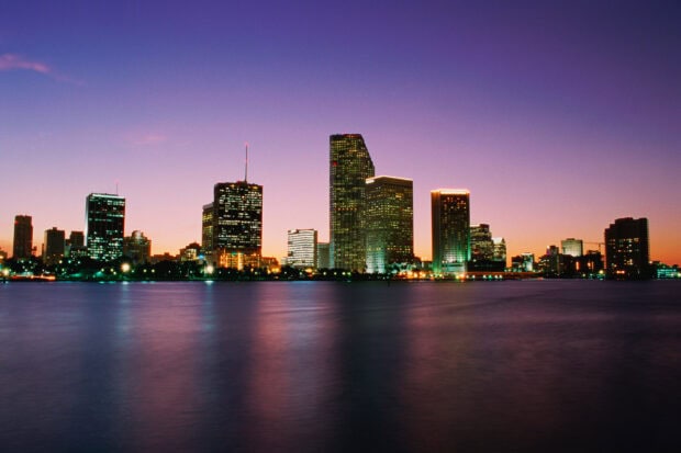 Miami Beach skyline with illuminated buildings reflecting over calm water at dusk