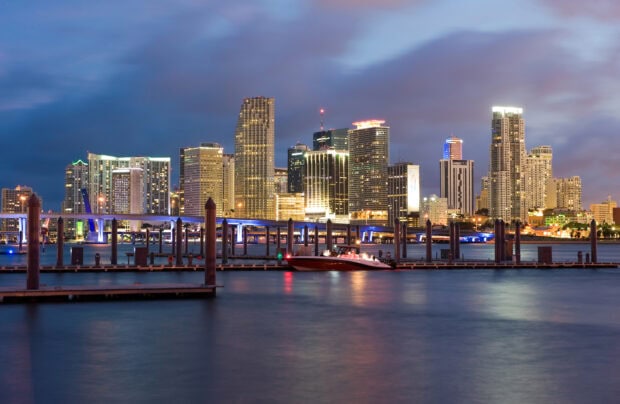 Night view of Miami Beach skyline with illuminated buildings and calm water across the harbor