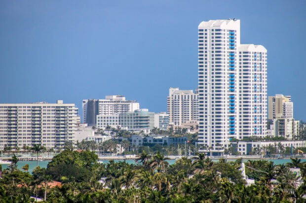 Tall Miami Beach skyline with modern buildings and lush greenery under clear blue sky