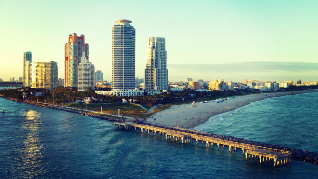 Miami Beach skyline viewed from the ocean with tall buildings and a pier in clear sky