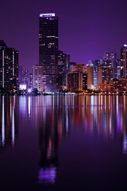 Night view of Miami Beach skyline with purple sky and city lights reflecting on water
