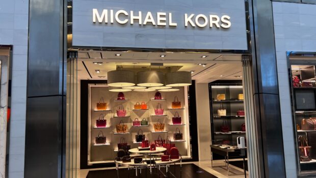 Michael Kors store display featuring various colorful handbags and accessories in a luxury retail setting
