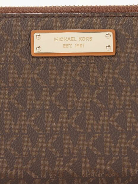 Close up of Michael Kors pattern on brown leather wallet with gold logo plate