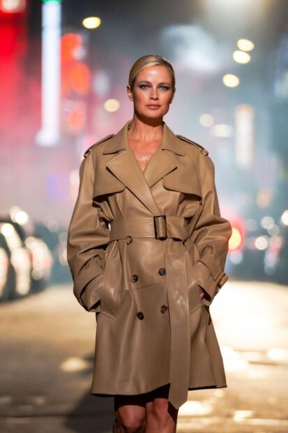 Woman wearing a stylish Michael Kors trench coat standing on a city street at night