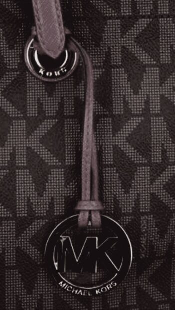 A close up of Michael Kors logo tag on a textured stylish fabric bag