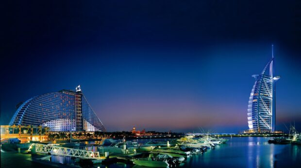 A night view of Middle East architecture featuring modern buildings and yachts in the harbor