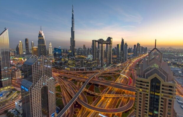 A stunning Middle East cityscape showing modern skyscrapers and intricate highway interchanges at sunset