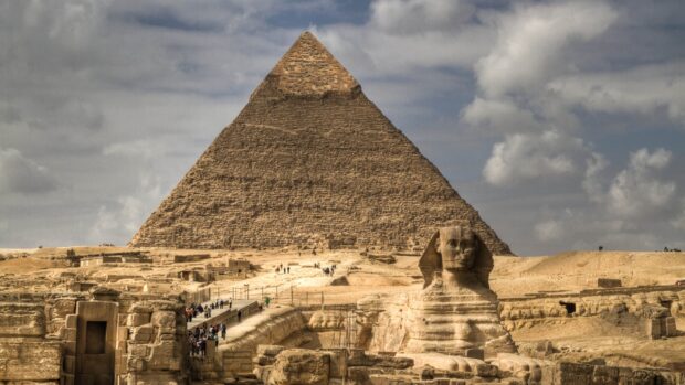 The Middle East ancient pyramid and sphinx under cloudy sky in a desert landscape