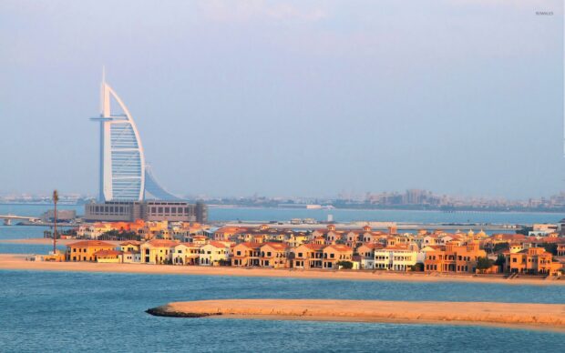 View of Middle East cityscape with iconic tower and coastal villas at sunset