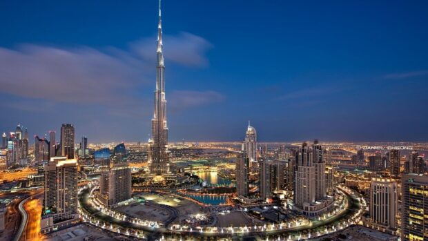 Illuminated cityscape of Middle East skyscrapers at night with a tall tower in the center