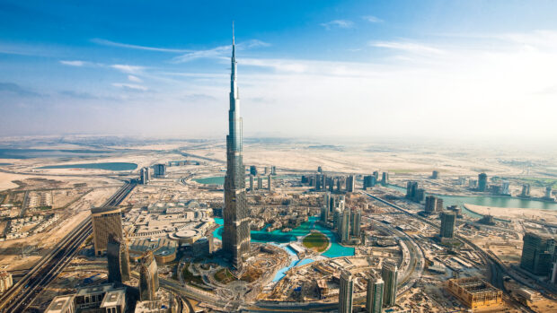 The Burj Khalifa tower stands tall in the Middle East city skyline surrounded by desert and modern buildings