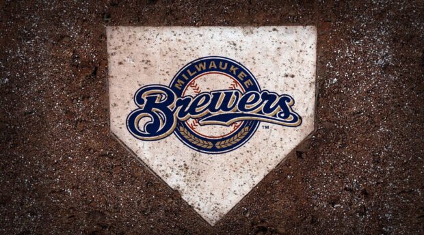 A close up of a Milwaukee Brewers logo on a baseball home plate surrounded by dirt