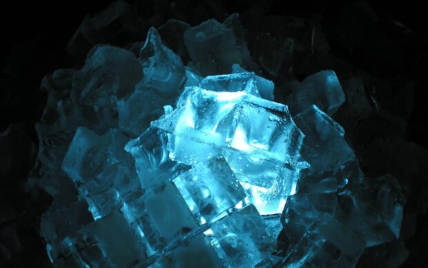 Transparent blue minerals with crystal like structure illuminated in dark surroundings