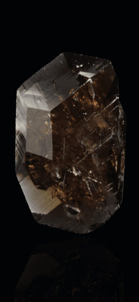 Dark brown transparent mineral with sharp faceted edges on black background