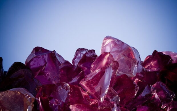 Transparent purple minerals under clear blue sky with natural light reflecting on surfaces