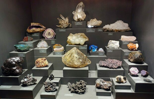 A collection of various minerals displayed on black stands showcasing natural formations and textures