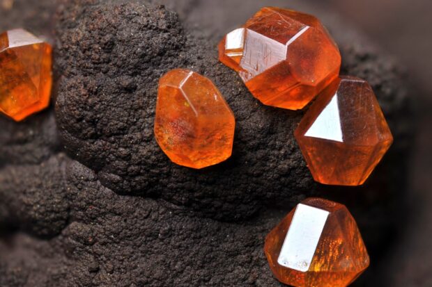 Close up of orange minerals on dark rough surface showing natural textures