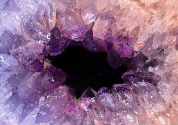 Close up view of minerals forming purple and pink crystal clusters with a dark center
