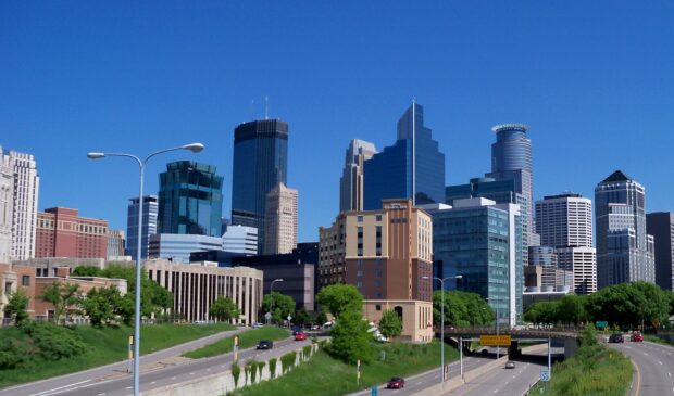 Clear blue sky over Minneapolis city skyline with highways and green trees in spring