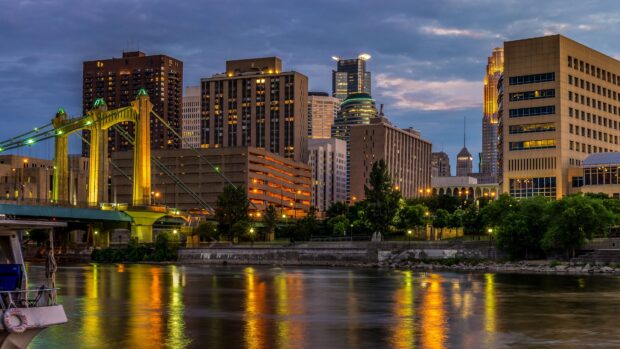 The Minneapolis city skyline with a bridge over the river during evening hours