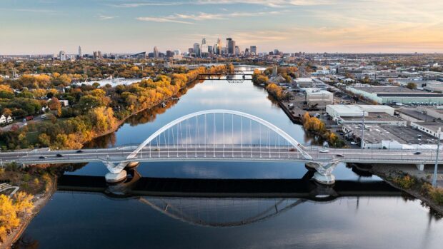 Aerial view of Minneapolis cityscape with a modern bridge over the river and autumn trees