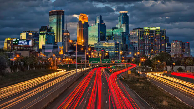 Nighttime cityscape of Minneapolis with busy highway and illuminated buildings