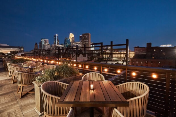 Cozy rooftop seating area with cityscape view of Minneapolis skyline at dusk