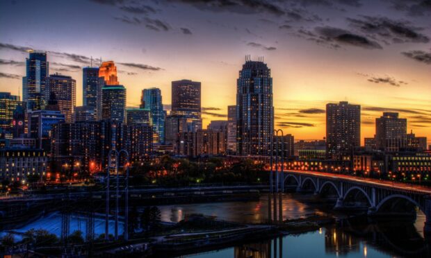 Minneapolis city skyline at sunset with skyscrapers and river bridge