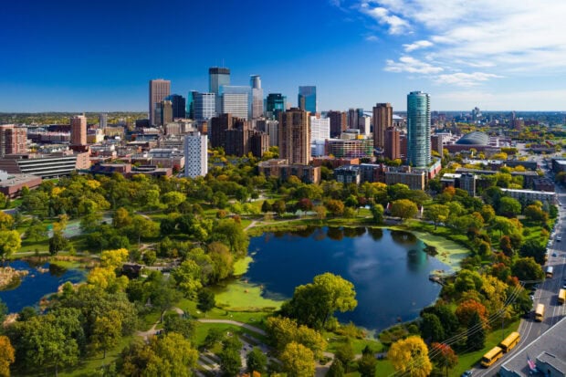 Aerial view of downtown Minneapolis with lush green park and lake in the foreground