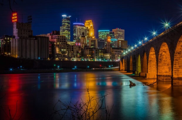 Night skyline with Minneapolis cityscape and stone arch bridge reflections