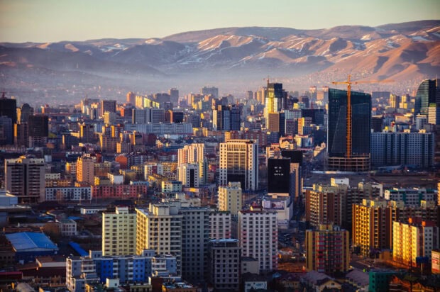 A panoramic view of Mongolia urban cityscape with mountains in the background during sunset