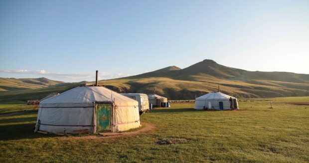 Traditional Mongolian tents set against rolling hills and a clear blue sky in Mongolia